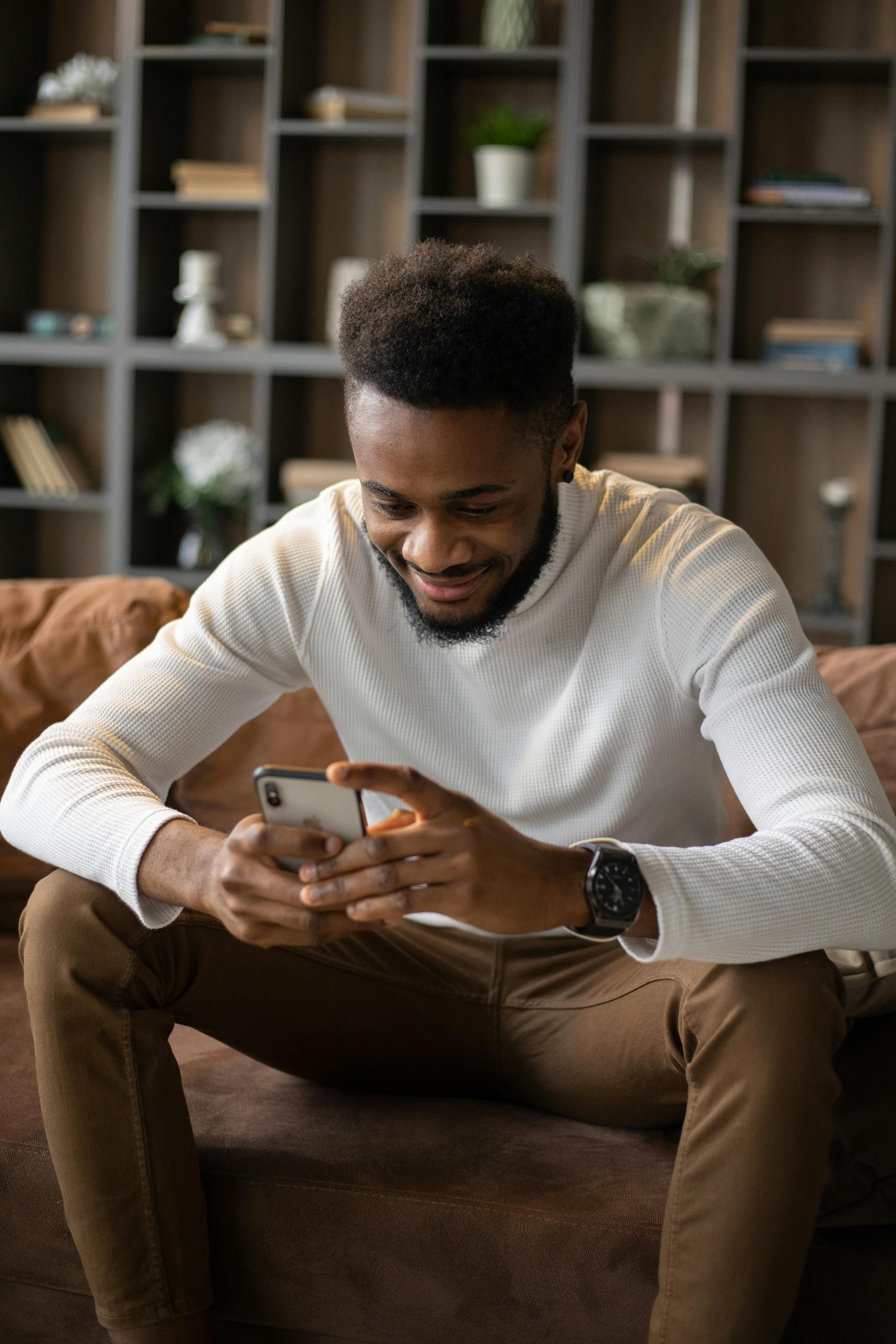 Cheerful man browsing on smartphone while relaxing at home.